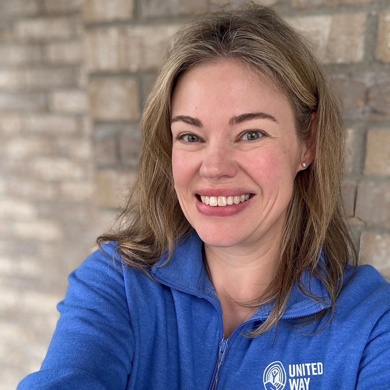 Laura wears a blue United Way shirt and smiles at the camera