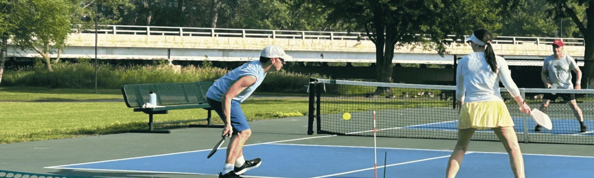 a mixed doubles pickleball team hitting a shot