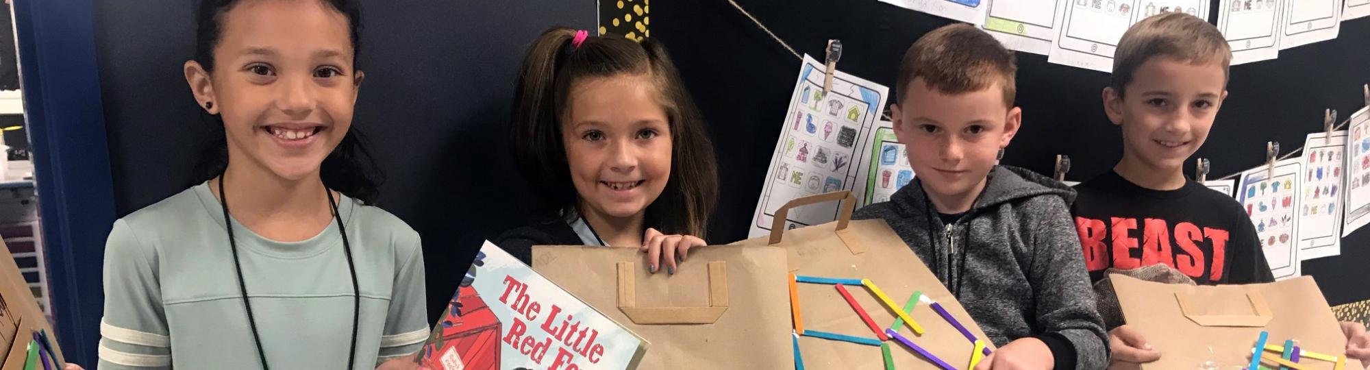 Smiling elementary school age kids holding school projects