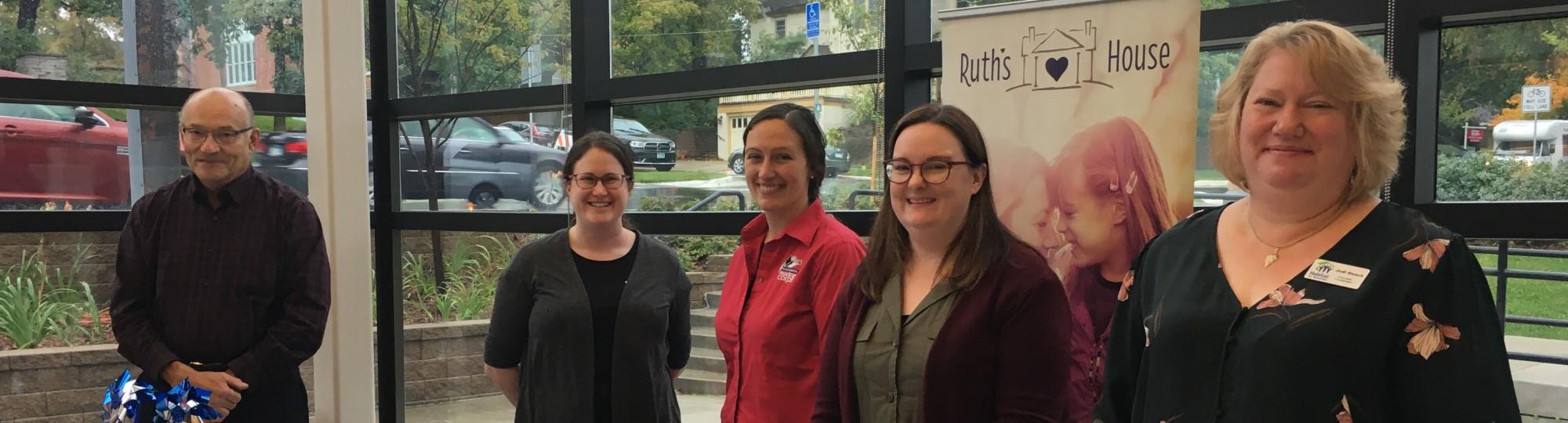 A man and four women representing United Way partner agencies in the atrium of the Northfield Public Library