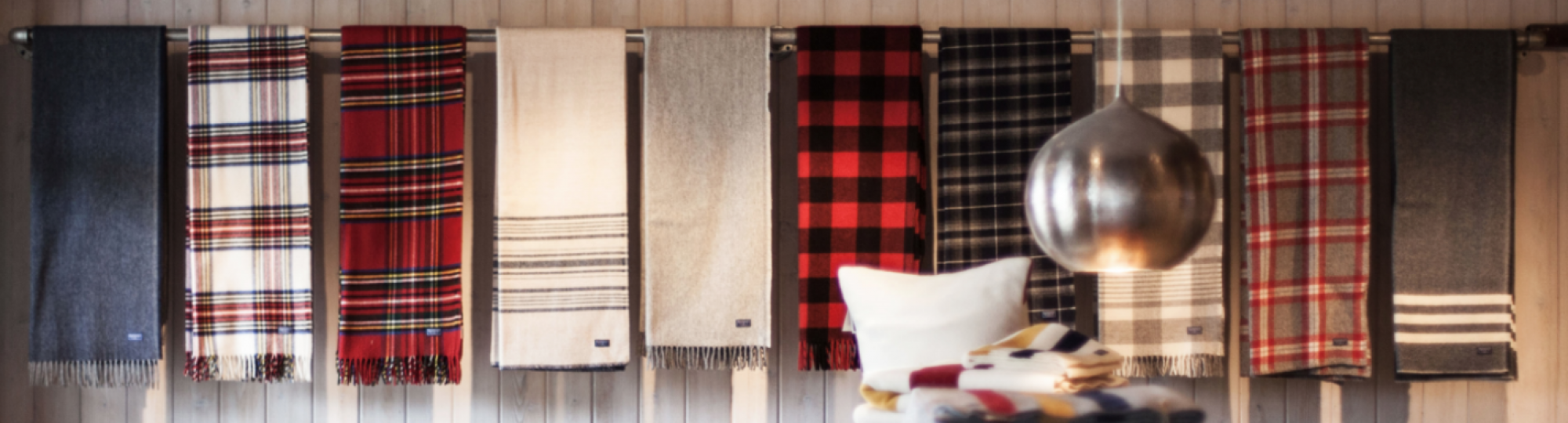 Folded blankets in colorful plaids hang from a railing