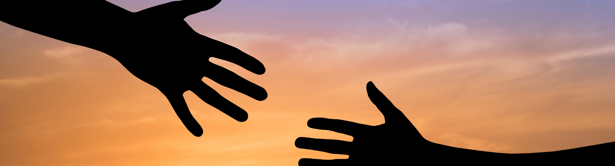 A helping hand reaches for another hand, silhouetted against a sunrise sky