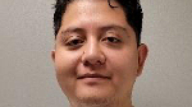 Francisco wears a white t-shirt and smiles at the camera