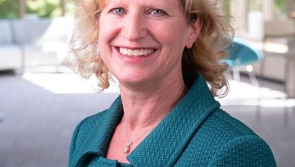 Kathy smiles at the camera wearing a teal jacket