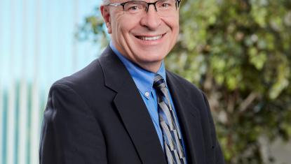 Peter wears a tie and smiles at the camera