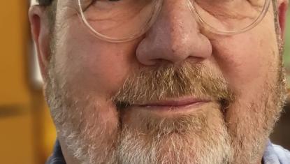 Dave wears glasses and a plaid shirt