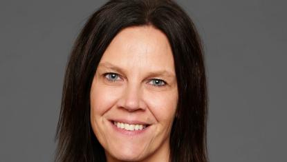 Tanya has brown hair and smiles at the camera