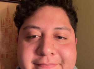 Francisco wears a grey shirt and looks at the camera